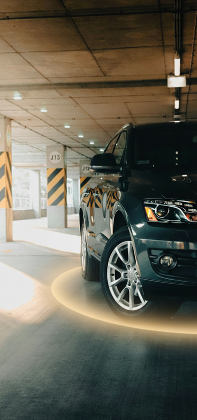 Ein dunkler SUV, der in einem gut beleuchteten Parkhaus geparkt ist, mit einem leuchtend gelben Ring um den Vorderreifen und gestreiften Säulen im Hintergrund – ein perfektes Beispiel für Parkraummanagement in modernen Hotelanlagen, das bequemes und effizientes Parken gewährleistet. - Sevoria Parking