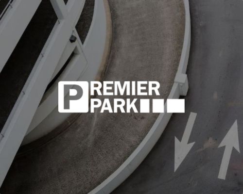 Das „Premier Park“-Logo in weißer Schrift vor dem Hintergrund einer geschwungenen Parkrampe und einer Straße mit weiß aufgemalten Pfeilen, die nach vorne und nach links zeigen, spiegelt die Effizienz des modernen Parkraummanagements für Parkraumbereiche im Einzelhandel und im Hotelgewerbe wider. - Sevoria Parking