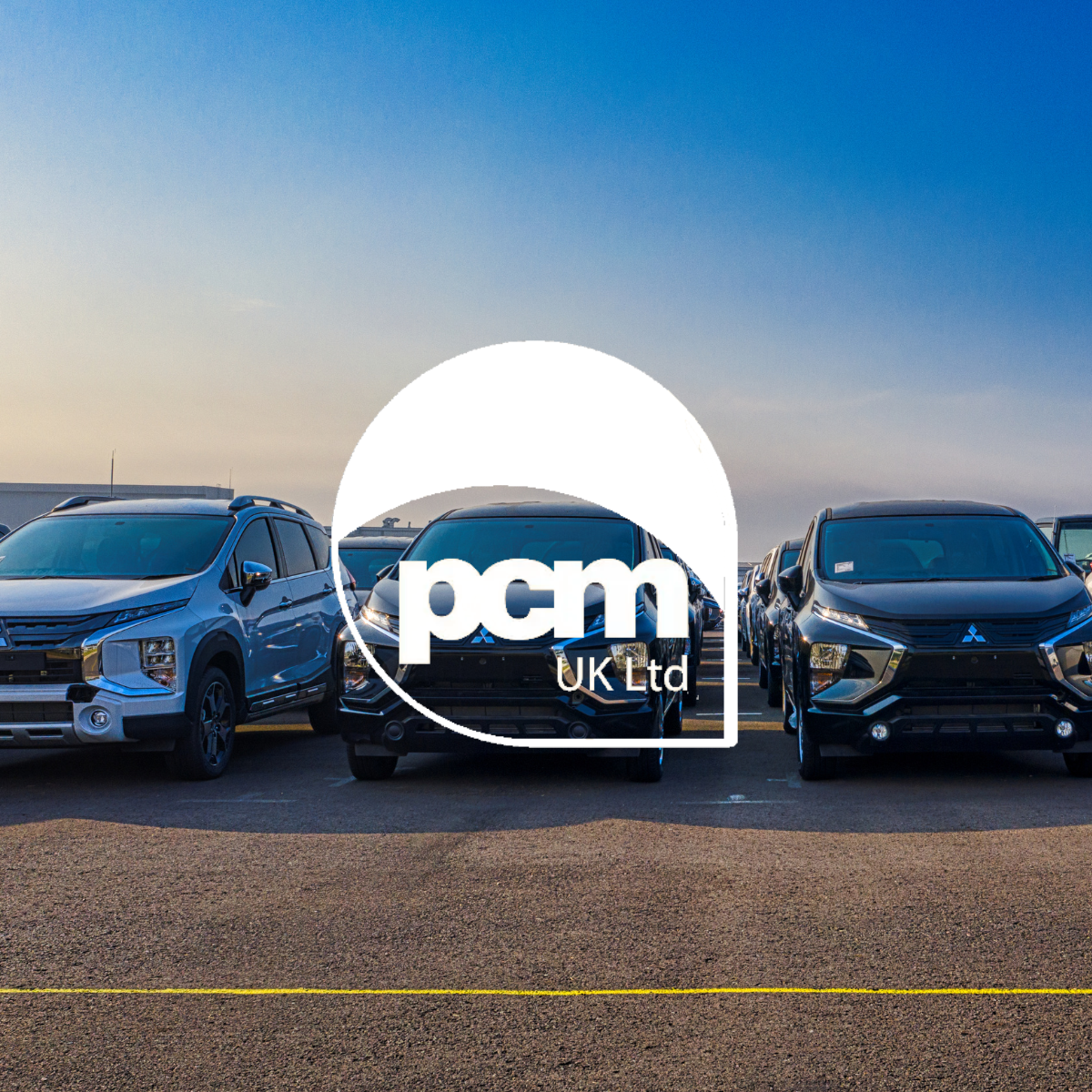 Mehrere geparkte Mitsubishi-SUVs stehen im Freien unter strahlend blauem Himmel in einer Reihe und verdeutlichen so ein effizientes Parkraummanagement. Ein großes weißes Logo von „pcm UK Ltd“ ist gut sichtbar in der Bildmitte eingeblendet. - Sevoria Parking